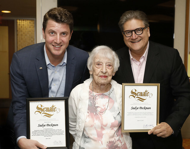 Older woman being awarded by two certificate